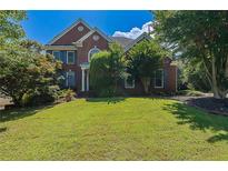 Beautiful brick home with manicured lawn, lush landscaping, and charming architectural details at 901 Chadwick Park Dr, Lawrenceville, GA 30045