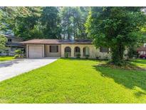 Charming single-story home with a well-maintained front yard and a driveway leading to an attached garage at 1105 Buckhurst Dr, Atlanta, GA 30349