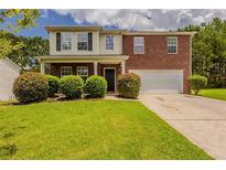 Charming two-story home with a well-manicured lawn, lush bushes, and a brick and siding facade, inviting and well maintained at 440 Pinevale Ct, Atlanta, GA 30349