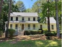 Inviting two-story home with a charming front porch and well-manicured lawn surrounded by mature trees at 340 Sherwood Se Cir, Conyers, GA 30094