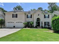 Stately home featuring a manicured lawn, arched entryway, and a convenient two-car garage at 5245 Cottage Farm Rd, Johns Creek, GA 30022