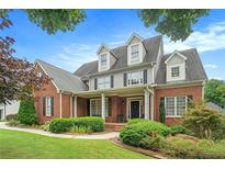 Charming two-story brick home featuring a welcoming front porch, lush landscaping, and a well-maintained lawn at 4653 Glory Maple Trce, Powder Springs, GA 30127