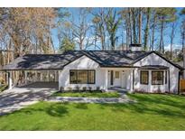 Charming home with white brick, a covered parking area, lush green lawn, and professional landscaping at 335 Amberidge Nw Trl, Atlanta, GA 30328