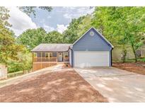 Charming blue home with a spacious front yard, inviting porch, and a convenient two-car garage at 7074 Babbling Brook Dr, Jonesboro, GA 30236