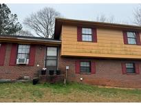 Two story home featuring a brick facade with red shutters and yellow siding at 5790 Twain Dr, Ellenwood, GA 30294