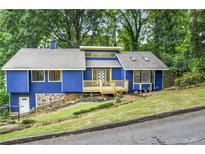 Charming blue home featuring a stone foundation, a welcoming front porch, and lush green landscaping at 468 Watson Ferry Dr, Forest Park, GA 30297