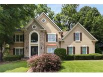 Charming front elevation of tan home with stone accents, black trim, and professionally landscaped yard at 820 Chelsea Park Ne Dr, Marietta, GA 30068