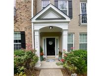 Charming home entrance with a black door, welcoming wreath, and lovely landscaping with colorful flowers at 11352 Musette Cir, Alpharetta, GA 30009