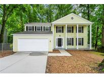 Charming two-story home with a two-car garage and a welcoming front porch surrounded by lush greenery at 1386 Heritage Glen Dr, Marietta, GA 30068
