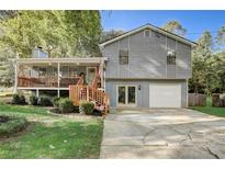 Charming gray home featuring a welcoming front porch, lush landscaping, and an attached garage at 151 Quail Hollow Dr, Dallas, GA 30157