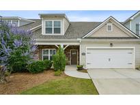 Charming home featuring a two-car garage, stone accents, and a beautifully landscaped front yard at 1637 Short Shadow Ln, Snellville, GA 30078