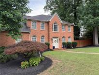 Charming two-story red brick home with a beautifully landscaped front yard and a welcoming front door at 200 Creek Run Ct, Alpharetta, GA 30005