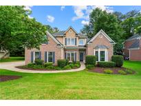 Charming brick home featuring lush landscaping, dark shutters, and a welcoming front entrance at 1995 Settindown Dr, Roswell, GA 30075