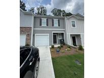 Charming two-story townhome with a one car garage, welcoming landscaping, and neutral gray tones at 2554 Coventry Sw St, Atlanta, GA 30331
