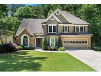 Charming two-story home featuring a stone and stucco facade, well-manicured lawn, and an attached two-car garage at 77 Skyland Dr, Roswell, GA 30075