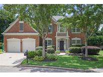 Traditional brick home featuring a two-car garage, manicured lawn, and mature trees at 2023 Belridge Se Ct, Smyrna, GA 30080