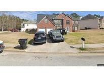 Two-story brick home featuring a two-car garage and a well-manicured front lawn at 696 Tomahawk Pl, Austell, GA 30168