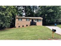 Charming ranch-style home featuring a brick facade, complemented by a well-manicured lawn and mature trees at 2443 Abner Nw Pl, Atlanta, GA 30318