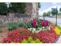 Landscaped neighborhood entrance with stone monument and colorful flowers for a welcoming and attractive curb appeal at 6426 Queens Court Trce # 7, Mableton, GA 30126
