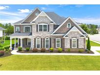 Charming brick and stone home with a manicured lawn and covered front porch at 4105 Vista Pointe Dr, Cumming, GA 30028