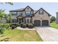 Charming two-story brick home with a well-manicured lawn and an attached two-car garage at 2183 Trinity Grove Ct, Dacula, GA 30019