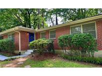 Charming brick home featuring a bright blue front door and well-maintained landscaping at 1403 Dennis Dr, Decatur, GA 30032