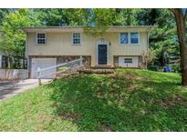 Split-level home featuring a cream-colored facade, stone accents, and an attached garage at 2242 Cherokee Valley Cir, Lithonia, GA 30058