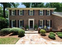 Charming brick home featuring a well-manicured lawn and a welcoming front entrance and stone walkway at 6960 Hunters Branch Dr, Atlanta, GA 30328