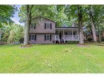 Charming two-story home with a covered front porch nestled among mature trees and a lush green lawn at 3110 Ashly Cove Ln, Snellville, GA 30078