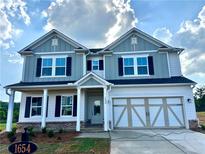 Charming two-story home featuring a two-car garage, inviting porch, and beautifully designed front facade at 1654 Tide Mill Rd, Cumming, GA 30040