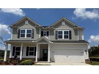 Charming two-story home featuring a covered porch, gray siding and a two car garage at 1654 Tide Mill Rd, Cumming, GA 30040