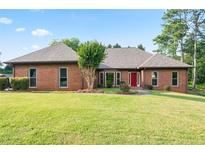 Charming brick home featuring a well-manicured lawn and a striking red front door at 300 Saddle Creek Ln, Roswell, GA 30076