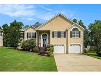 Charming two-story home featuring manicured lawn, two car garage, and classic front door with decorative window at 4077 High Country Dr, Douglasville, GA 30135