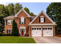 Charming two-story brick home featuring a well-maintained lawn, two-car garage and inviting red front door at 1767 Tidewell Trce, Lawrenceville, GA 30043
