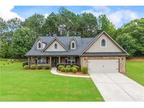 Charming home with stone and siding exterior, well-manicured lawn, and attached two-car garage at 1524 Guthrie Crossing Dr, Loganville, GA 30052