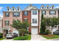 Charming brick townhome with dormer windows, manicured landscaping, and a private drive at 7863 Kiverton Pl, Atlanta, GA 30350