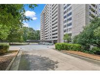 View of building exterior showing a covered parking area with well-maintained landscaping and manicured bushes at 3530 Piedmont Ne Rd # K8, Atlanta, GA 30305