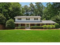 Charming two-story home boasts a brick facade, manicured lawn, and lush landscaping at 4984 Wickford Way, Atlanta, GA 30338