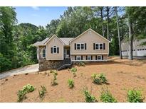 Charming tan home with stone accents, black shutters, and landscaped front yard at 400 Hunt River Way, Suwanee, GA 30024