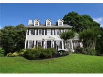 Charming two-story home featuring gray siding, black shutters, dormer windows, and a well-manicured front lawn at 5040 Puritan Dr, Sugar Hill, GA 30518