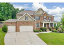 Inviting two-story brick home with a well-manicured lawn, two-car garage, and a charming front porch at 1211 Fawndale Nw Dr, Kennesaw, GA 30152