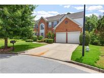 Well-maintained two-story brick home with a two-car garage, lush lawn, and mature trees at 5003 Pacific Dunes Dr, Suwanee, GA 30024