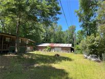 Lush, expansive yard with trees and a storage shed, featuring a house with a covered porch at 195 Darla Dr, Woodstock, GA 30188