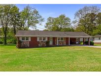 Charming brick and stone home featuring a well-manicured lawn and covered carport at 3031 Walker Dr, Marietta, GA 30062