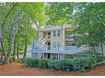 Two-story condo with a light yellow exterior, white railings, and surrounded by mature trees at 1202 Countryside Pl, Smyrna, GA 30080