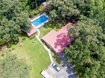 Aerial view of the home with in-ground pool, green lawn, mature trees, and a red roof at 7234 Post Rd, Winston, GA 30187