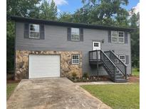 Charming two-story home featuring a stone facade, gray siding, and a well-maintained front yard with flower beds at 6906 Shangrila Way, Riverdale, GA 30296