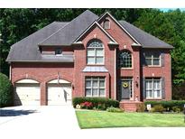 Charming two-story red brick home with arched windows, shutters, attached garage and manicured front lawn at 3930 Regal Oaks Dr, Suwanee, GA 30024