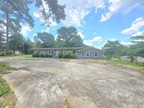 Charming single-story home with a large driveway and well-lit windows nestled among mature trees at 4945 Campbellton Sw Rd, Atlanta, GA 30331