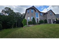 Two-story brick home with a well-manicured lawn, mature trees, and a two-car garage at 2819 Heritage Oaks Cir, Dacula, GA 30019